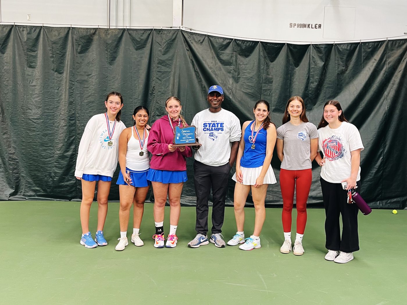 Ron Bronson with his high school tennis team holding a championship plaque
